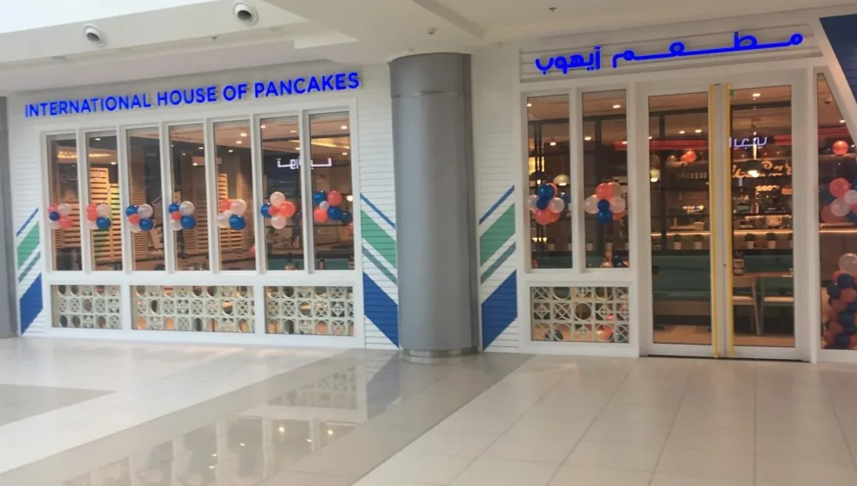 A completed IHOP storefront with bilingual signage, blue and white tilework, and balloon displays at the entry.